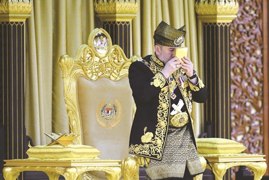 Sultan Mohamed V kissing a copy of the Holy Quru2019an during his coronation at the National Palace in Kuala Lumpur yesterday.