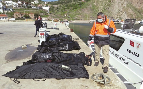 A rescuer walks next to bodies of migrants in body bags laid on a pier at the Aegean port village of Babakale in Canakkale province, Turkey, next to a Turkish coast guard vessel, after an inflatable boat carrying them sank off the Greek island of Lesbos.