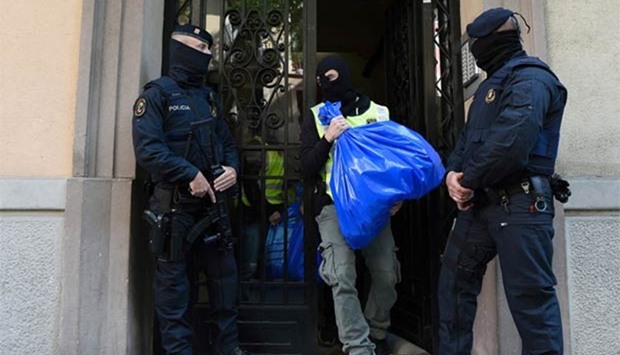 A member of the Catalan Regional Police carries a garbage bag during a raid on a flat in Barcelona on Tuesday that led to the arrest of four men accused of collaborating with Islamic militants.