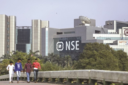 Pedestrians walk past the National Stock Exchange of India building in Mumbai. The benchmark Nifty closed above the 9,300-mark for the first time in its history yesterday, while the Sensex soared 287 points to a three-week high on widespread buying, spurred by strong results and upbeat global cues.