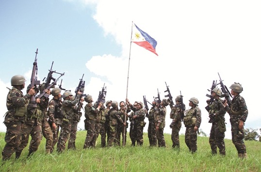 Soldiers hoist a national flag after clashes with Islamic State-affiliated extremists in the mountain area of Piagapo town, Lanao del Sur province, on the southern island of Mindanao yesterday.