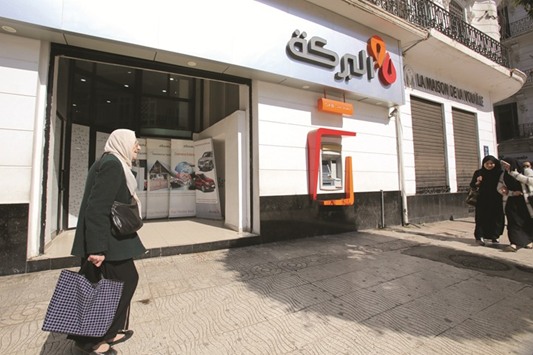 A woman walks past a branch of Al Baraka Bank in Algiers city on April 5. With the economy emerging from decades of centralised control, Algeria badly needs alternatives to the energy revenues that have traditionally financed 60% of the budget.
