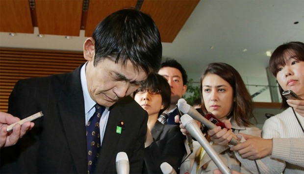 Surrouded by reporters, Japan's Disaster Reconstruction Minister Masahiro Imamura bows after submitting his resignation
