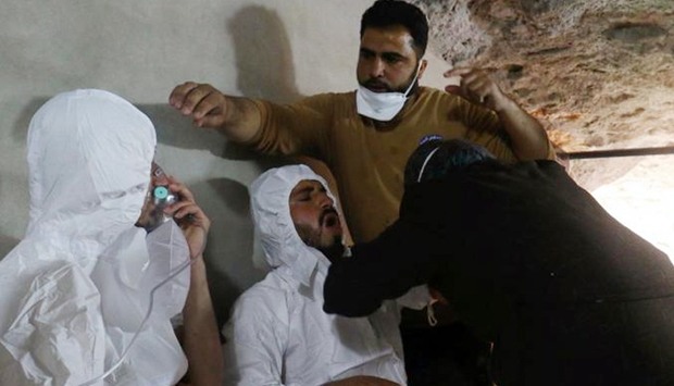 FILE PHOTO: A man breathes through an oxygen mask as another one receives treatments, after what rescue workers described as a suspected gas attack