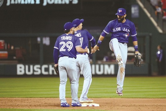 Toronto Blue Jays right fielder Jose Bautista (R) celebrates with shortstop Ryan Goins and second baseman Devon Travis (L) after defeating the St. Louis Cardinals in eleven innings at Busch Stadium. PICTURE: USA TODAY Sports