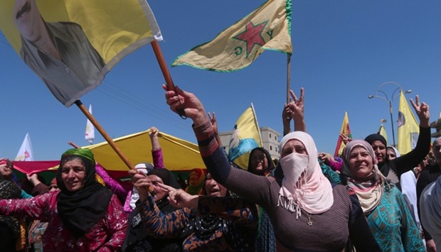 Kurdish women carry flags as they protest, in the northeastern city of Qamishli, against Turkish airstrikes on the headquarters of the Kurdish fighters from the People's Protection Units (YPG) in Mount Karachok on Tuesday.