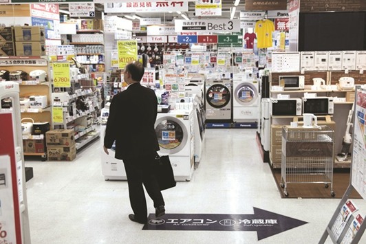 A man walks in a store selling electric household goods in Tokyo. Japanu2019s central bank chief said that policymakers would not slow down their monetary easing programme until their 2% goal had been achieved.