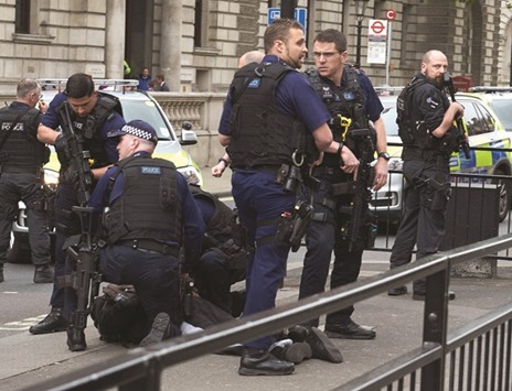 Police officers detain a man near the Houses of Parliament in central London yesterday.