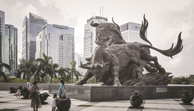 People stand in front of a sculpture of bulls at the entrance to the Shenzhen Stock Exchange building in China. A $1.7tn source of inflows into Chinese markets has suddenly switched into reverse, roiling the nationu2019s money management industry and sending local bonds and stocks to their biggest losses of the year.