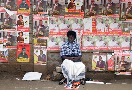 This picture taken on Wednesday shows a woman in front of campaign posters waiting to cast her ballot, during the Jubilee Party primary elections, at a polling centre in Nairobi.