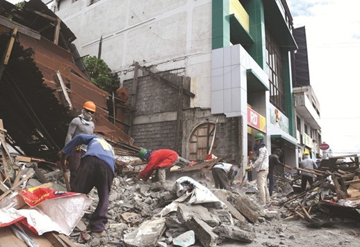 Workers remove debris from a collapsed house after a 6.8-magnitude earthquake hit General Santos City, in southern island of Mindanao yesterday.