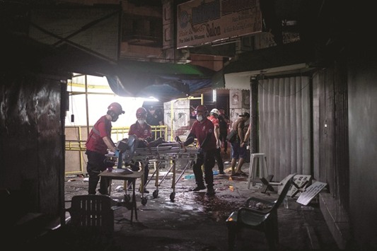 Rescue workers attend to a wounded man on a stretcher in an alley in Manila yesterday, after a homemade pipe bomb exploded.