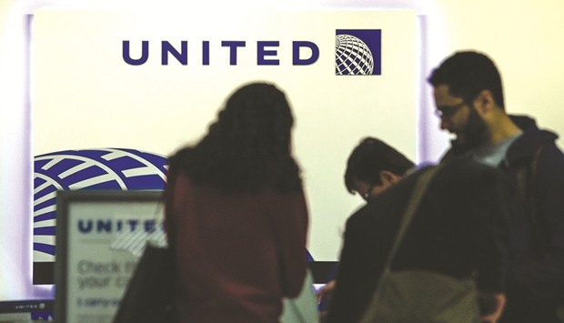 Passengers use self check-in kiosks inside the United Continental Holdings terminal at Newark Liberty International Airport in Newark, New Jersey, US. United has reached a settlement with a passenger who was dragged off a plane and bloodied. It also said it would pay as much as $10,000 to passengers who agree to give up their spots, following a similar move by Delta.