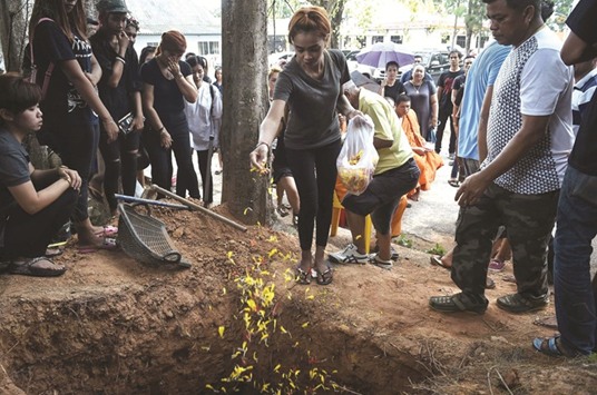 Jiranuch Trirat throws chrysanthemum petals into the grave of her 11-month-old daughter Natalie in Phuket yesterday.