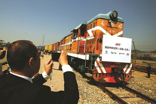 An official takes pictures as a train carrying containers from London chugs into the freight railway station in Yiwu, Zhejiang province. The sign at the front of the locomotive reads u2018First Sino-Euro Freight Train (London Yiwu)u2019.