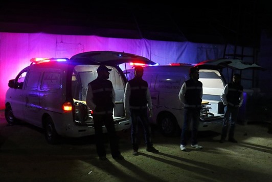 Medics stand outside ambulances as they wait the arrival of people who evacuated the besieged Waer district in the central Syrian city of Homs, in Idlib province, Syria yesterday.