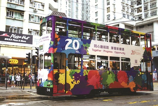 Commuters travel on a tram with a design commemorating the 20th anniversary since the city was handed back to China by colonial ruler Britain in a residential Hong Kong neighbourhood.