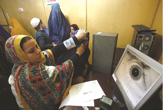A United Nations High Commission for Refugees official carries out an IRIS test on an Afghan refugee at the UNHCR office on the outskirts of Peshawar, Pakistan, yesterday.