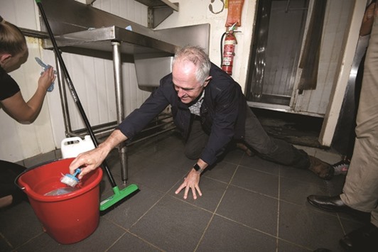 Australian Prime Minister Malcolm Turnbull helps with cleaning at a flood-damaged restaurant in Lismore.