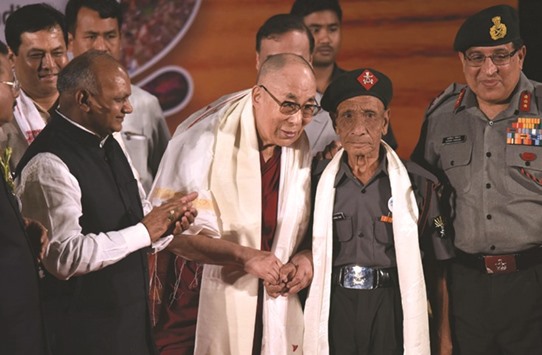 Tibetan spiritual leader the Dalai Lama shakes hands with retired Assam Rifles personnel Naren Chandra Das, the lone known survivor of a group of seven Indian personnel who were the first to receive the Dalai Lama on Indian soil after he fled Tibet, during an event in Guwahati.