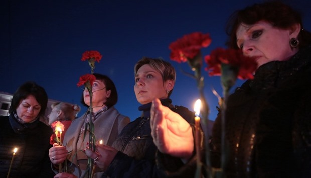Women hold flowers and lit candles as they take part in a gathering in memory of victims of the blast in the Saint Petersburg metro in Simferopol, Crimea.