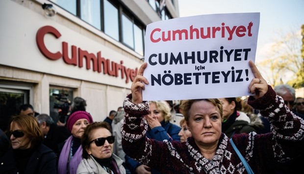 A protester holding a sign reading ,We are here for Cumhuriyet, in front of opposition Cumhuriyet newspaper in Istanbul, after a police operation at the daily's headquarters. October 31, 2016 file picture. AFP