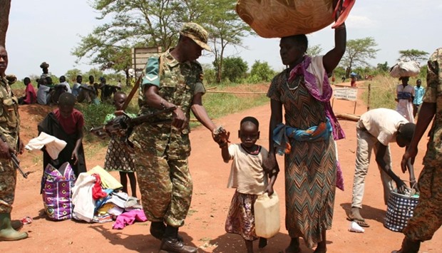 A Uganda People's Defence Forces (UPDF) soldier receives South Sudanese refugees crossing into Uganda at the Ngomoromo border post in Lamwo district, northern Uganda.