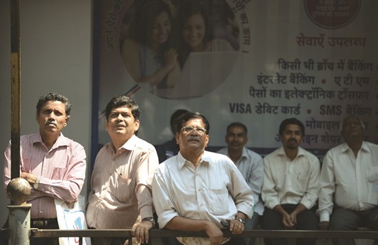 Bystanders watch share prices displayed on a digital broadcast on the facade of the Bombay Stock Exchange building in Mumbai. The BSE Sensex closed up 0.21% to 29,974 points yesterday.