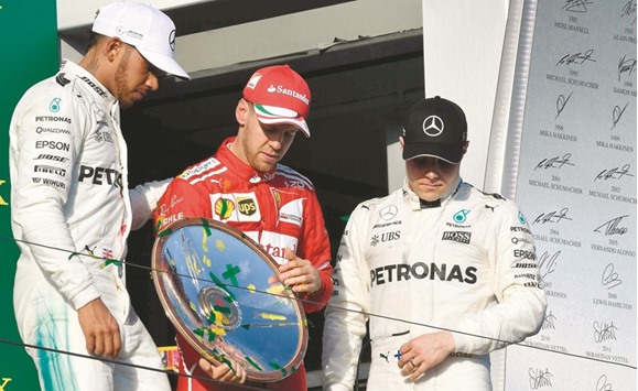Ferrariu2019s Sebastian Vettel (centre) holds the winneru2019s trophy with second-placed Mercedes driver Lewis Hamilton (left) and third-placed Valtteri Bottas on the podium for the Australian Grand Prix in Melbourne last month. (AFP)