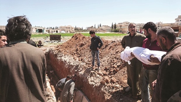 Syrians bury the bodies of victims of a suspected toxic gas attack in Khan Sheikhun, a nearby rebel-held town in the northwestern Idlib province, yesterday.