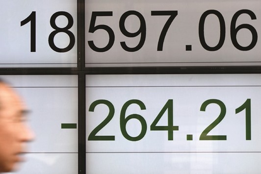 A man walks past a stock quotation board flashing the Nikkei 225 key index of the Tokyo Stock Exchange in front of a securities company in Tokyo. The index fell 1.4% to 18,597.06 after Federal Reserve minutes suggested the US central bank was considering steps that could result in a further tightening of monetary policy.