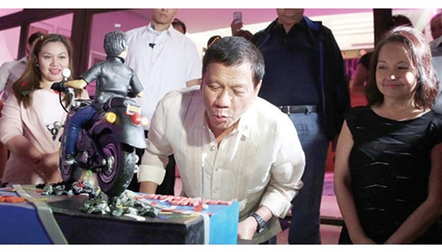 President Rodrigo Duterte blows the candle on a cake with a figure of himself on a motorbike. Duterte, who turned 72 on March 28, had his own birthday cake during the 70th birthday celebration of former president Gloria Macapagal Arroyo (right) in Lubao, Pampanga.