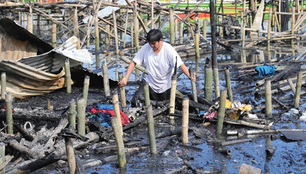 A coastal area resident wades through a river to search for valuable items after a fire engulfed hundreds of shanties and thousands of families lost their homes at a community of informal settlers local media reported, in Bacoor, Cavite city, south of Manila, yesterday.