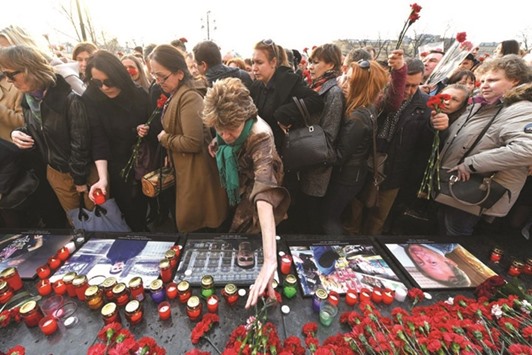 People place flowers and candles, in honour of the victims of April 3 blast in the Saint Petersburg metro, by a memorial stone reading Leningrad (an old name of Saint Petersburg) by the Kremlin wall during a commemorative event in central Moscow.