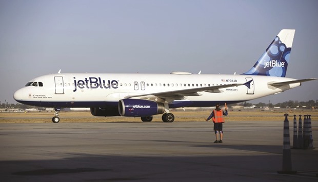 An aircraft marshaller guides a JetBlue Airways Corp aircraft on the tarmac at Long Beach Airport (LGB) in Long Beach, California. Boeing and JetBlue are joining a rush by aviation and aerospace companies to scout investments in early-stage ventures and keep tabs on technology with the potential to transform transportation.