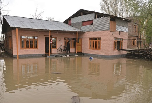 A Kashmiri resident walks through a flooded house on the outskirts of Srinagar yesterday.
