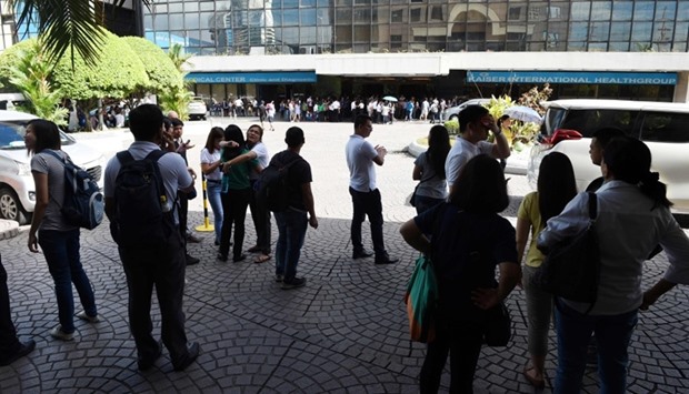 Office workers stand on the grounds of an office building in the financial district of Makati in Manila, after a 5.7 magnitude earthquake.