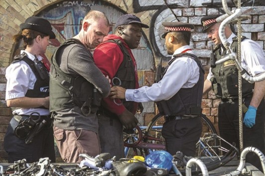 Police detain a man suspected of handling stolen goods during the raids near Brick Lane.