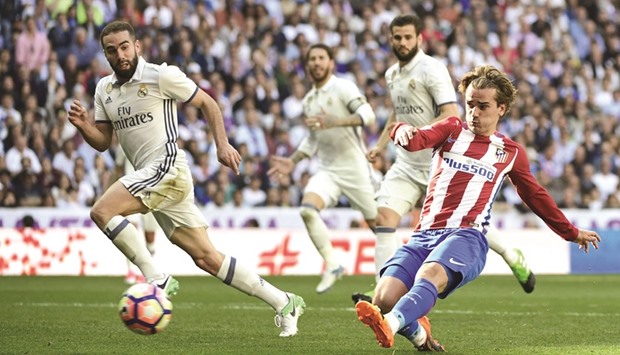 Atletico Madridu2019s forward Antoine Griezmann (right) scores during the Spanish La Liga match against Real Madrid at the Santiago Bernabeu stadium in Madrid yesterday. (AFP)