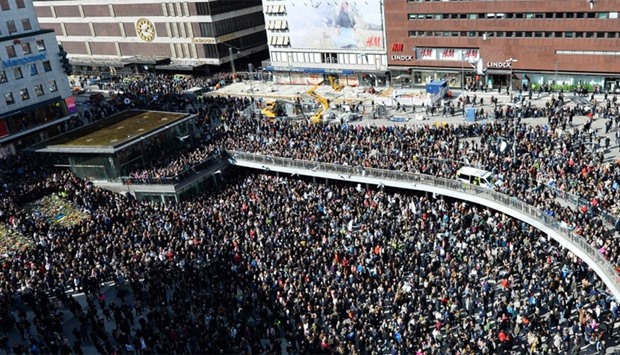 People attend a memorial ceremony at Sergels Torg plaza in Stockholm