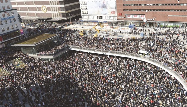 People attend a memorial ceremony yesterday at Sergels Torg plaza in Stockholm, close to the area where a truck was driven into a department store two days before.