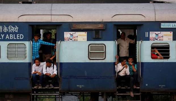 Commuters sit on the doorstep of a moving train in New Delhi