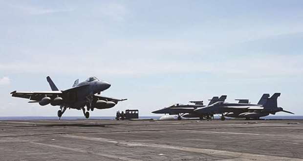 An F-18 fighter, on patrol, lands on the deck of the USS Theodore Roosevelt, transiting the South China Sea.