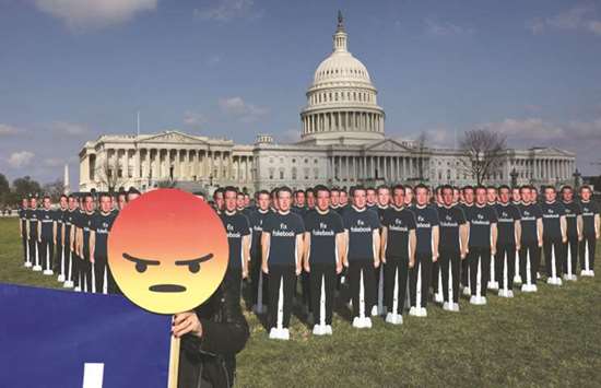 Chelsea Hornick-Becker of Avaaz.org holds a protest sign in front of dozens of cardboard cut-outs of Facebook CEO Mark Zuckerberg outside of the US Capitol Building in Washington yesterday.
