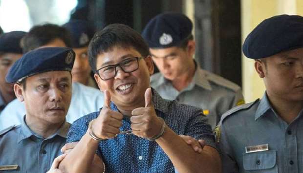 Detained  journalist Wa Lone (C) gives a thumbs up to reporters as he is escorted by police to a cou
