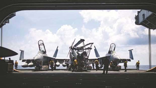 Sailors moving aircraft in the South China Sea, from an elevator into the hangar bay of the aircraft carrier USS Theodore Roosevelt (CVN 71), as Theodore Roosevelt is underway for a scheduled deployment in the US 7th Fleet area of operations in support of maritime security operations and theatre security co-operation efforts.