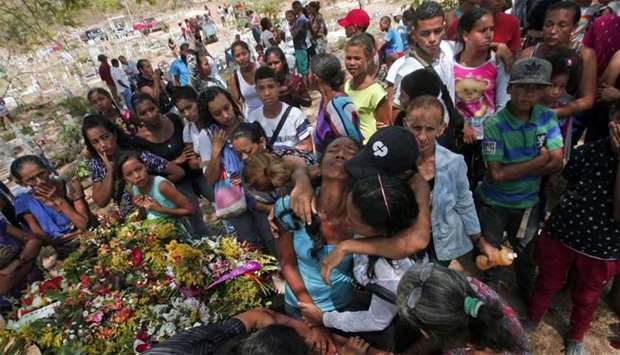 Relatives grieve during the funeral of the prisoners that perished after a police holding cells caught fire in Valencia, northern Carabobo state