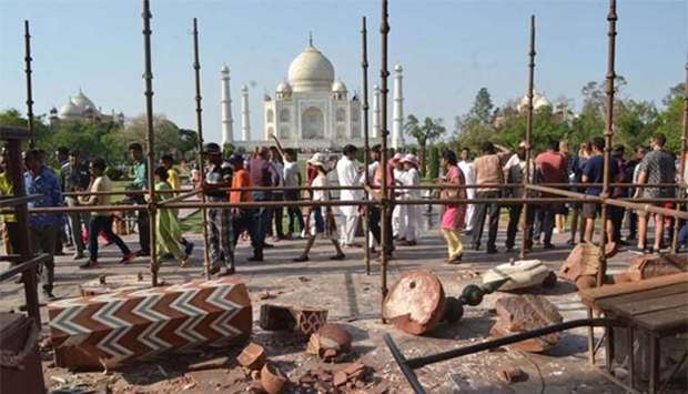 People gather around base of the Royal Gate entrance at the Taj Mahal complex next to a fallen minaret that collapsed during a storm in Agra on Thursday.