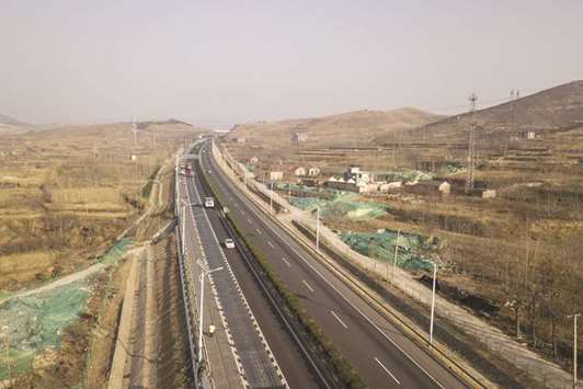Vehicles travel adjacent to photovoltaic lanes developed by Qilu Transportation Development Group Co (left) on a highway in this aerial photograph taken in Jinan, China on March 9. About 45,000 vehicles barrel over the 1,080-metre-long section every day, and the solar panels inside generate enough electricity to power highway lights and 800 homes, according to Qilu Transportation.