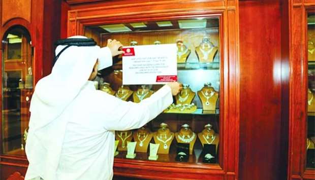 An official of the Ministry of Economy and Commerce puts up a violation notice at the jewellery store at Hyatt Plaza.